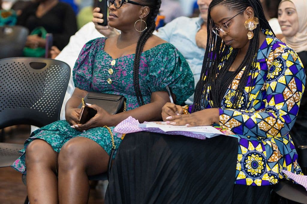 Two parents taking notes during a school meeting