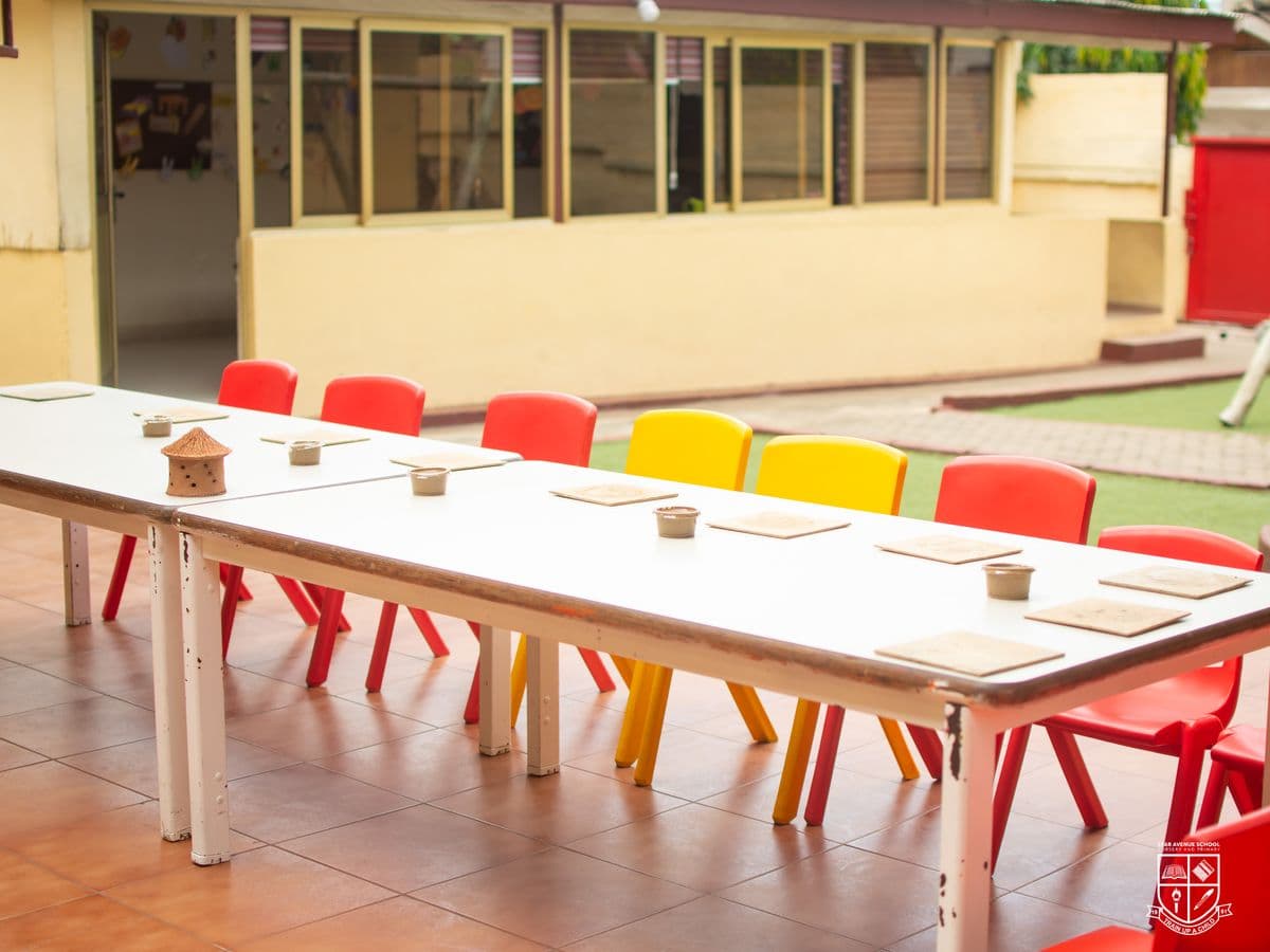 Tables and red and yellow chairs set out along the school veranda